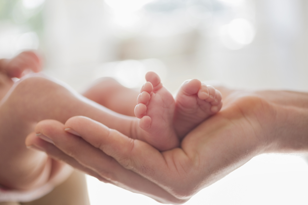 Mother cradling newborn baby's feet